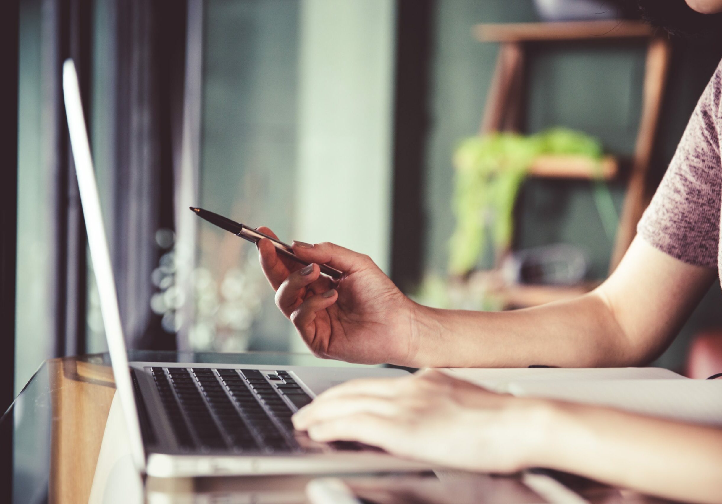 Beautiful young Asian woman working at a coffee shop with computer laptop. Pointing to the important information detail. Female freelancer connecting to internet via computer. Casual Thinking Browsing Concept.